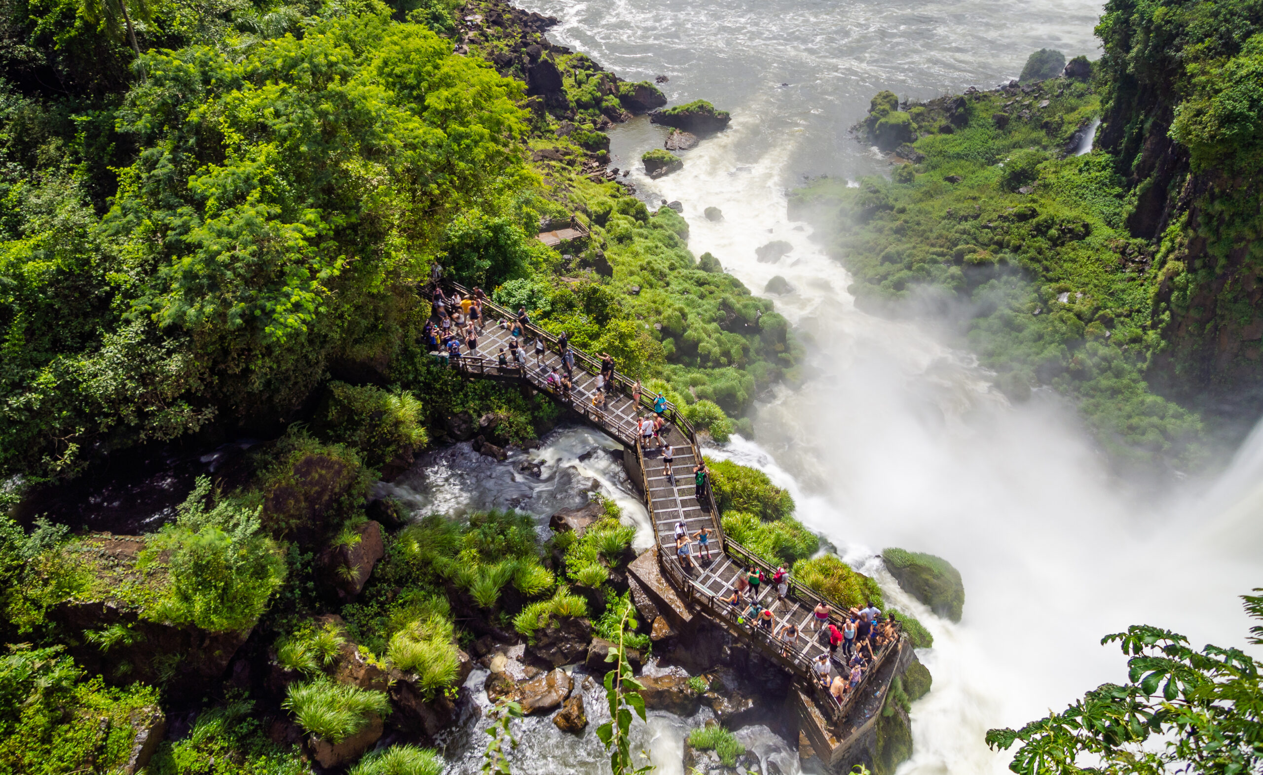 Magnificent drone view of group of tourists standing on terrace near beautiful Iguazu waterfall in Argentina